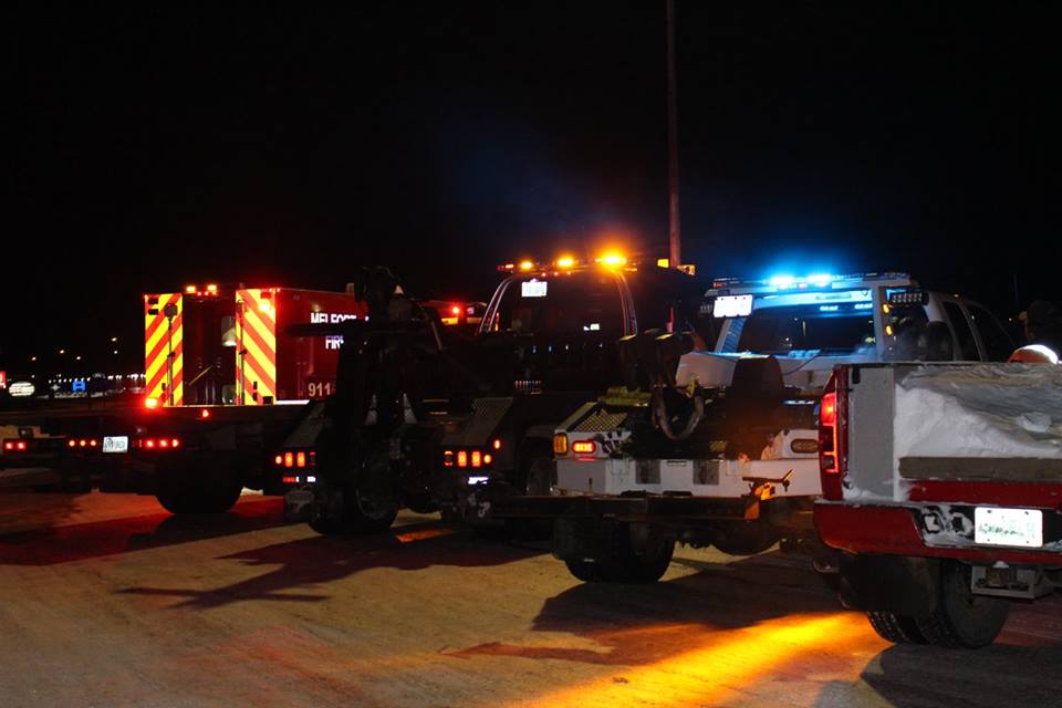 A night time picture of two tow trucks and a fire rescue vehicle participating in a rally or safety for tow truck operators