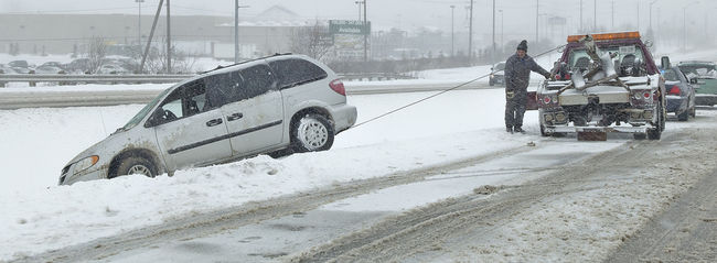A van getting hauled out of the ditch beside a highway in winter conditions